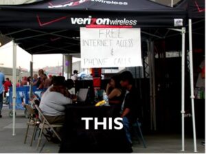 Image of people sitting at a table under a verizon tent with a sign that reads "Free Internet Access and Phone Calls" with the text "THIS" at the bottom of the image.