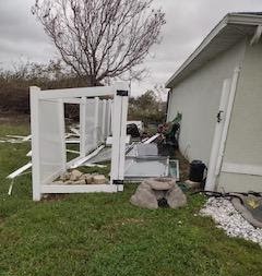 Image of a damaged side of a house with debris around due to hurricane Ian.